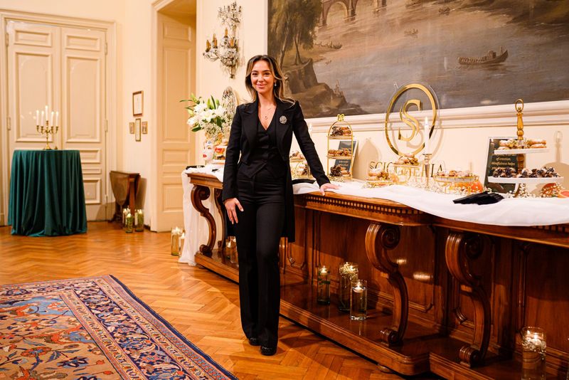 Claudia Militello într-un salon elegant, lângă un bufet cu desert